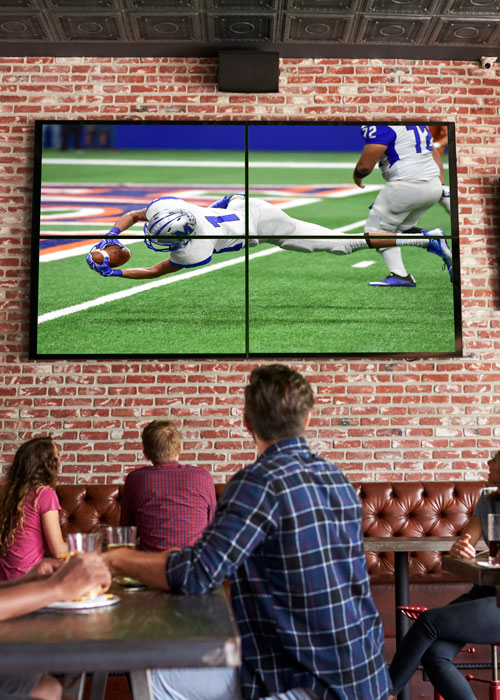 A restaurant with a video wall displaying a football game. 