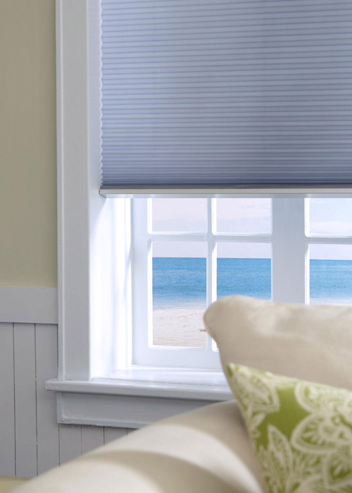 Cellular motorized shades lowered on a window with ocean view. 