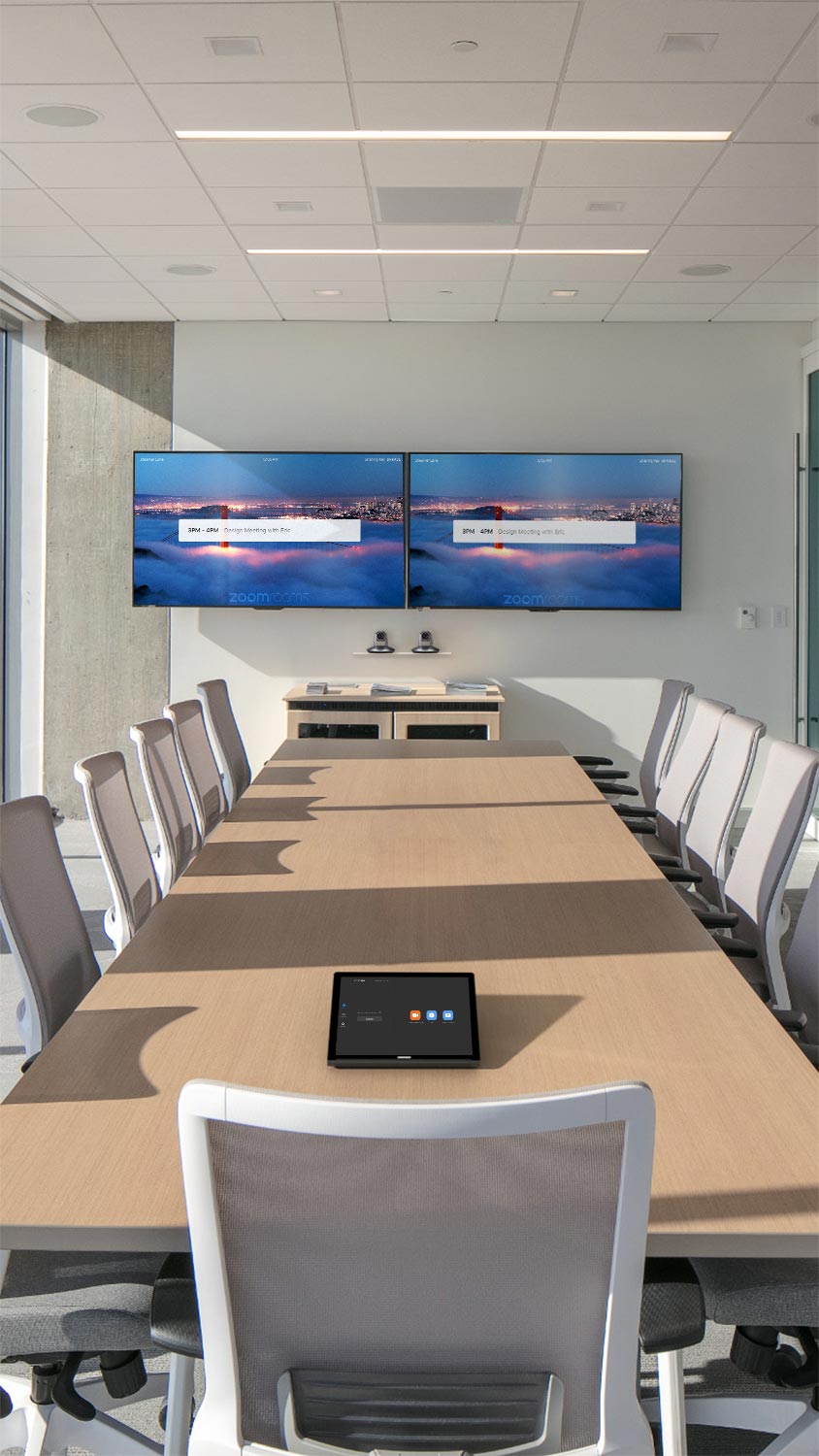 Bright conference room with dual screens and large table