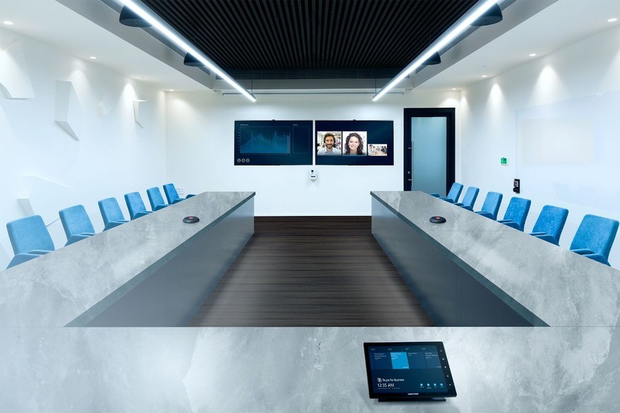 A large training room with two display screens and a tabletop control touchscreen.