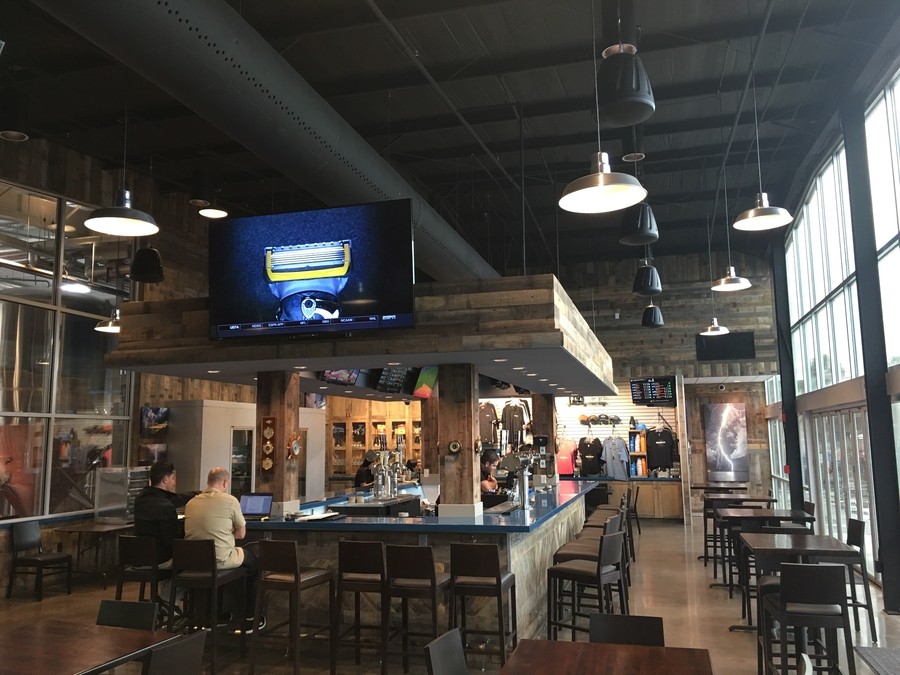 A sports bar with high-top stools, flat screen TVs, and a commercial sound system. 