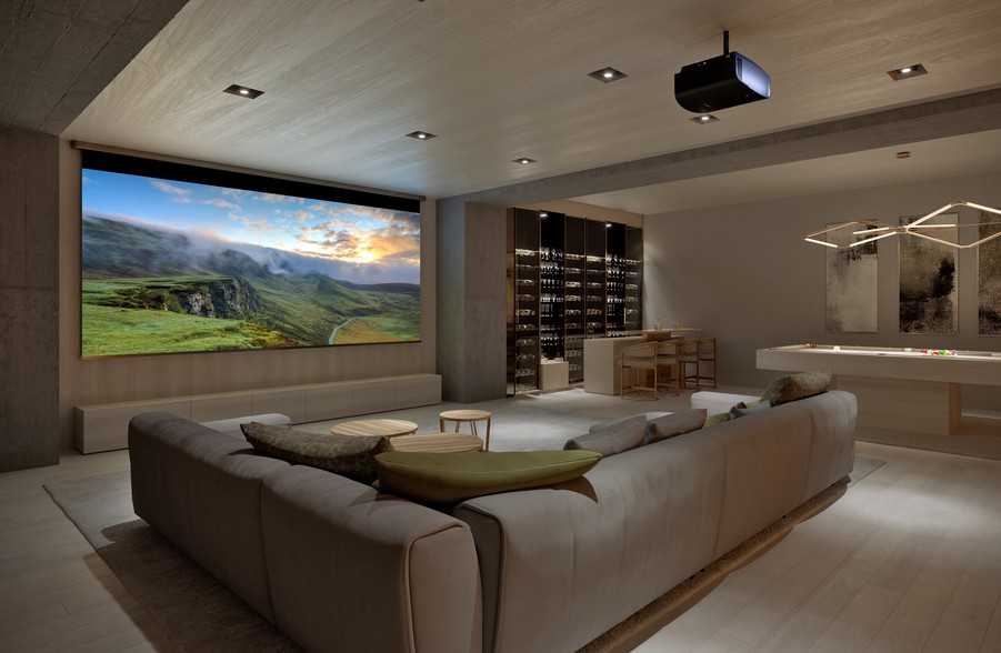 A casual home theater with a sectional, pool table, Sony projector, and movie screen.