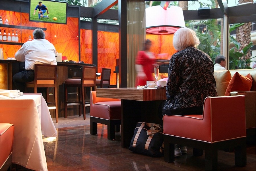 a woman stands up at a sports bar booth while a TV plays soccer in the background