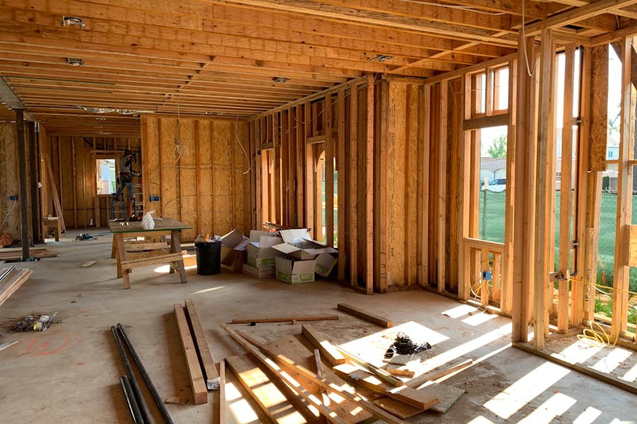 Interior view of a new home under construction with exposed wooden framing and electrical pre-wiring, highlighting the rough-in stage before drywall installation.
