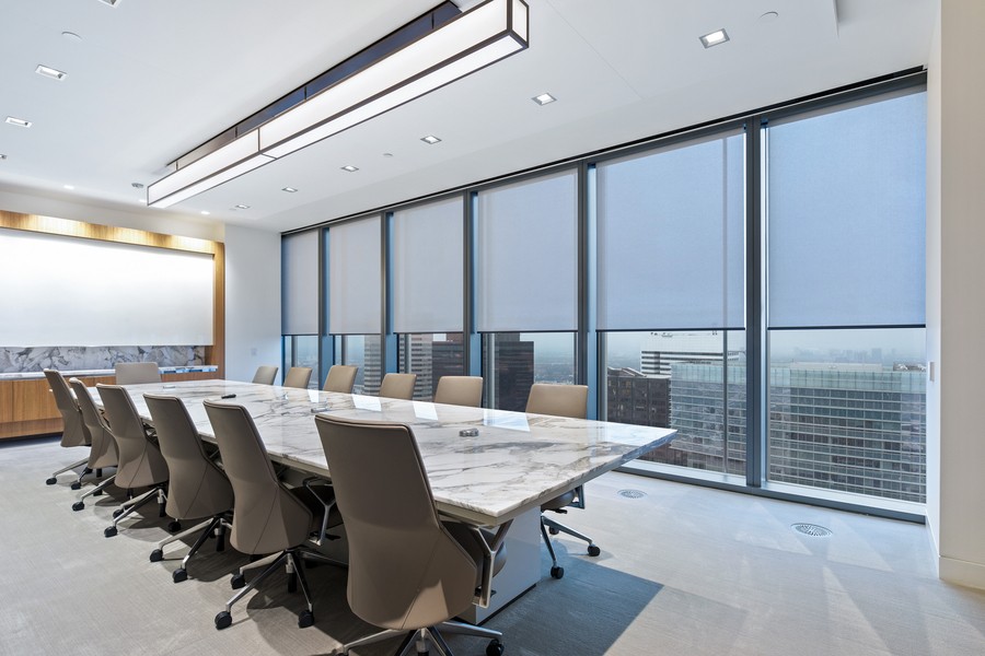 A modern conference room featuring motorized shading systems controlling natural light for optimal meeting conditions.