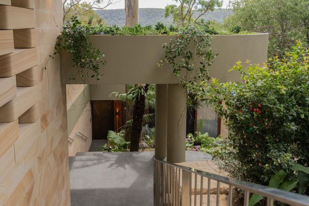 Outdoor walkway with stone walls and greenery surrounding entrance