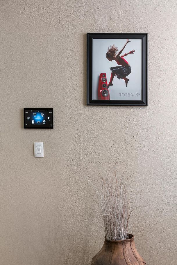 Smart home control panel on wall under framed Totem speaker artwork