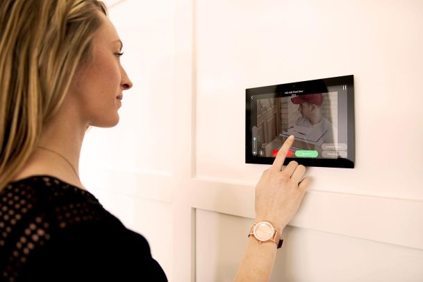Woman using wall-mounted smart home touchscreen panel