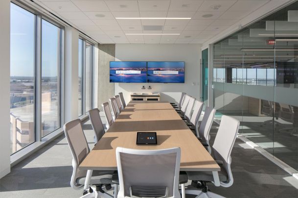 Bright conference room with long table and dual display screens
