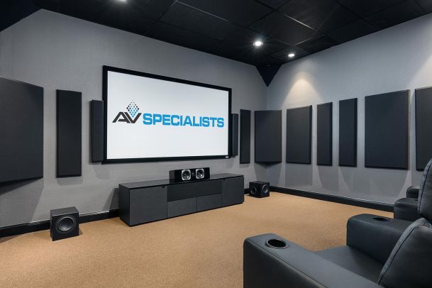 Home theater with large projection screen, acoustic panels, and leather seating