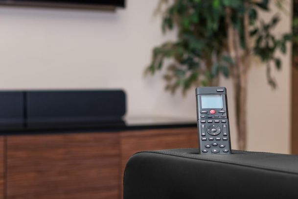 Remote control resting on black leather chair with cabinet in background