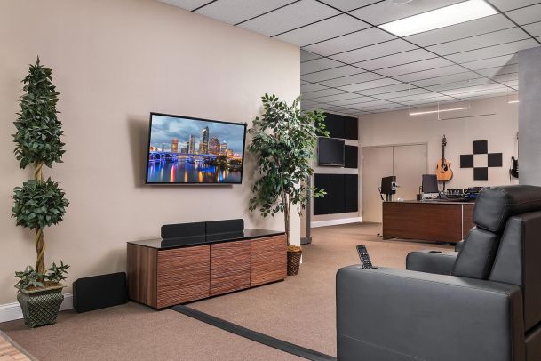 Showroom space with wall-mounted TV, leather chair, and potted plants