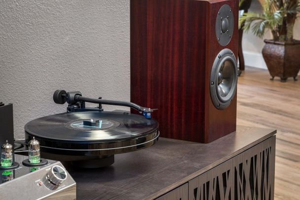 Turntable playing vinyl next to bookshelf speaker on cabinet
