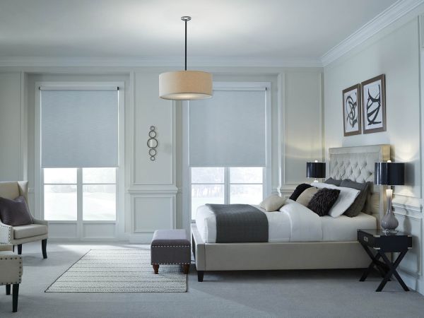 A bedroom with motorized shades on windows lowered halfway.