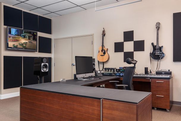 Office setup with desk, guitars on wall, and audio equipment