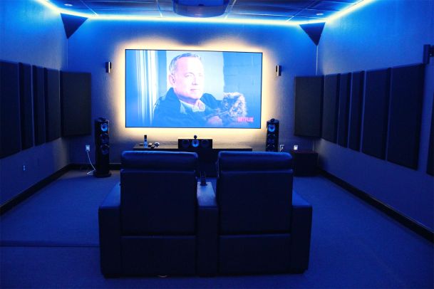 Private home theater with large screen, speakers, and blue LED lighting